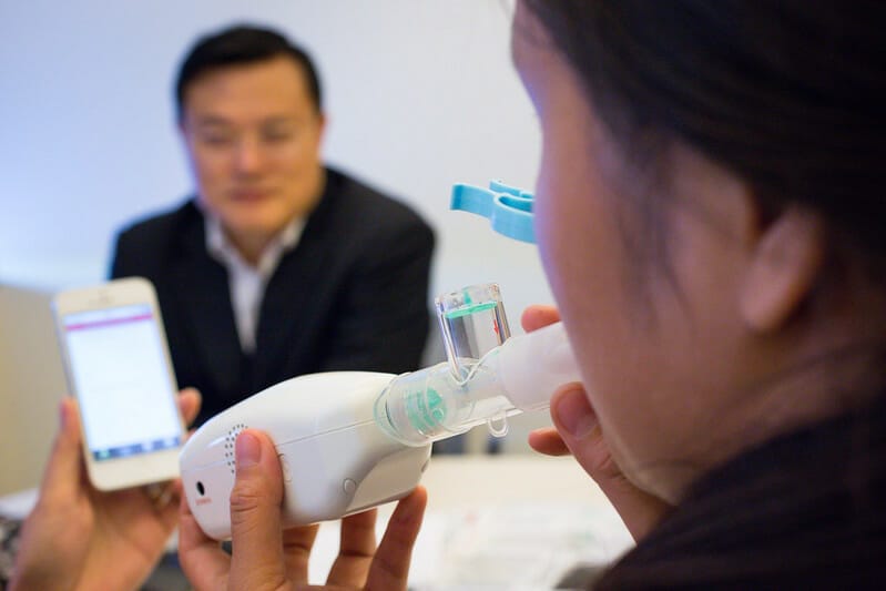 Person using breath sensor with phone app in background