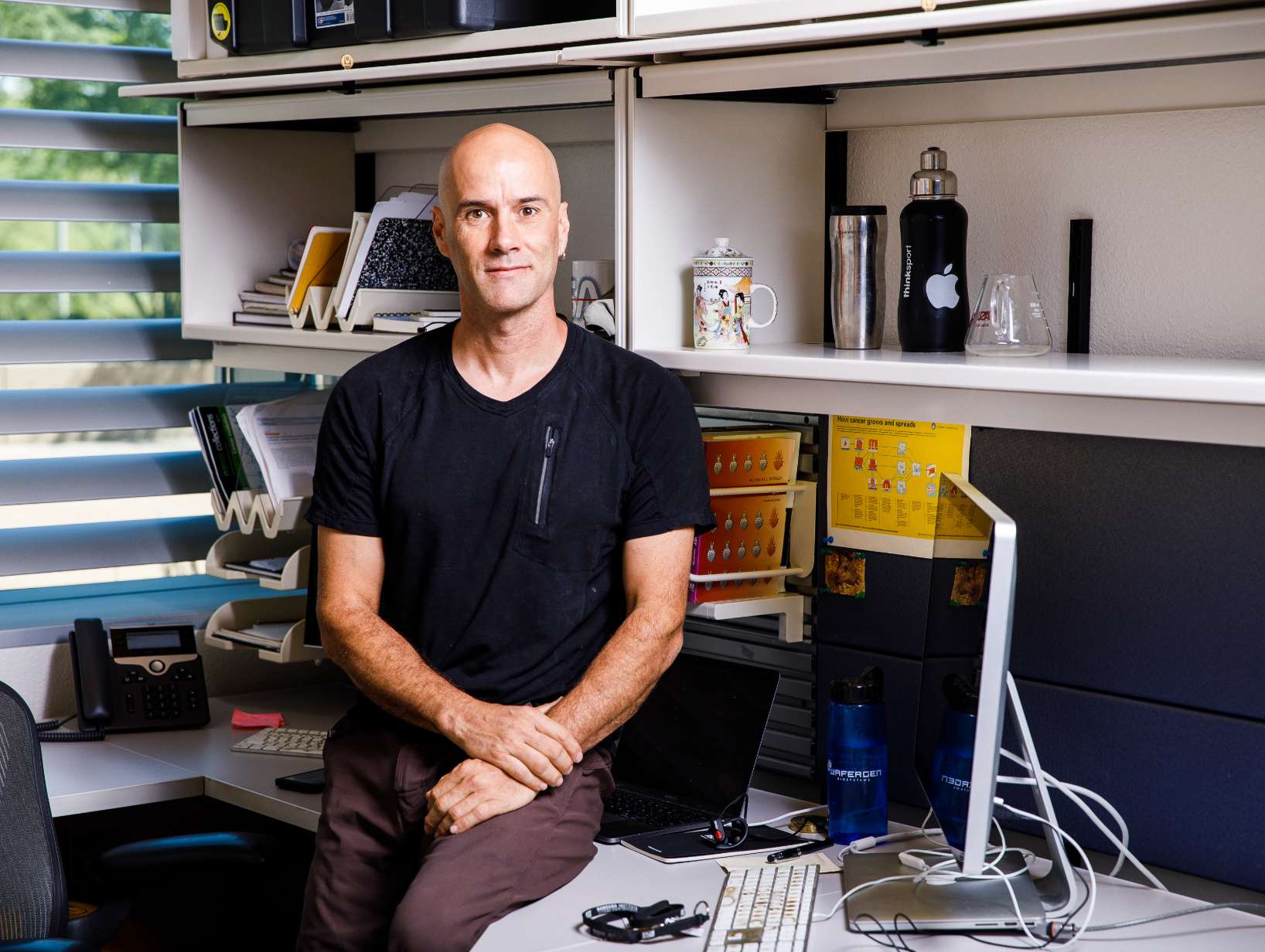 Man sitting on desk in office.